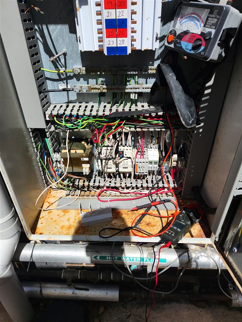 Insulation tester and multimeter leads connected inside a mechanical switchboard during testing